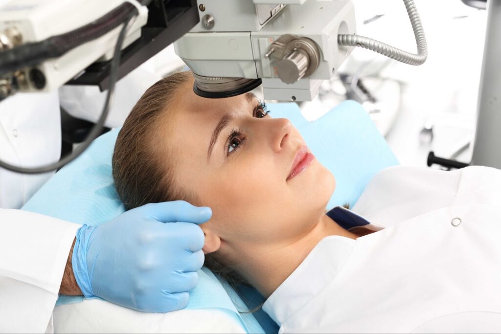 A surgeon adjusts the eye laser on a female patient.