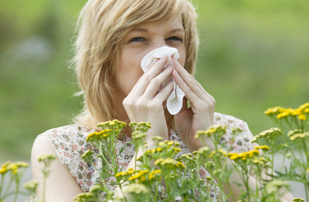 Woman blowing her nose due to pollen allergy.
