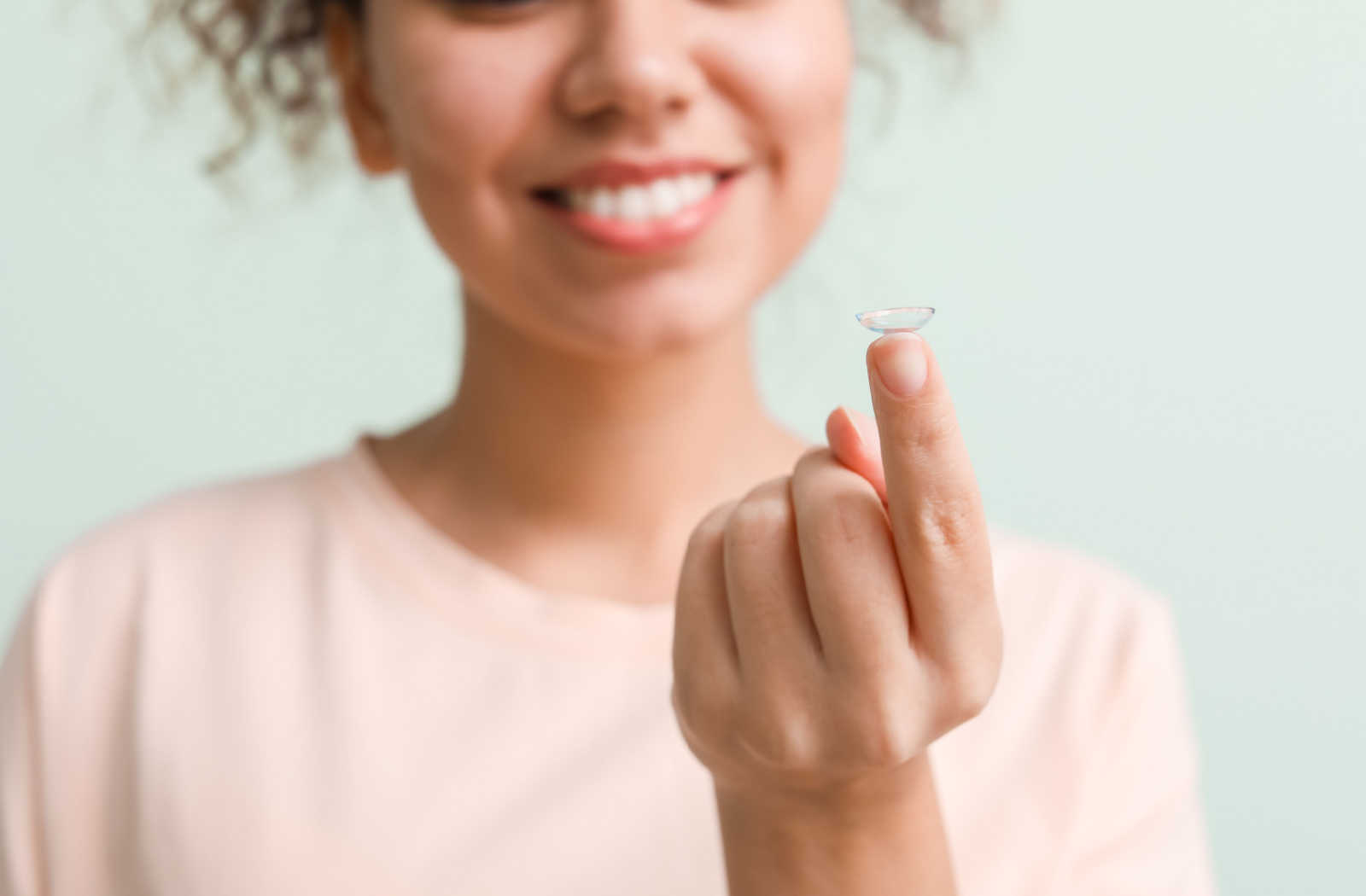 Young woman holding a contact lens on her pointer figer.