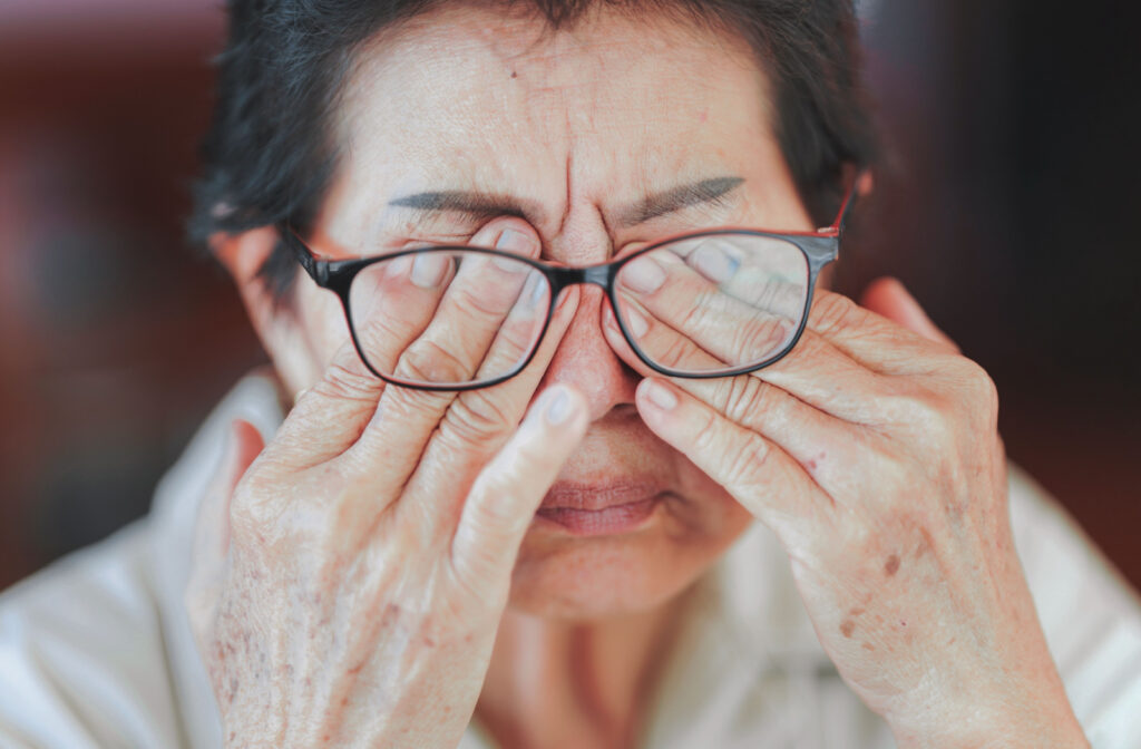 A senior woman pushing her glasses up with her fingers as she rubs her eyes.