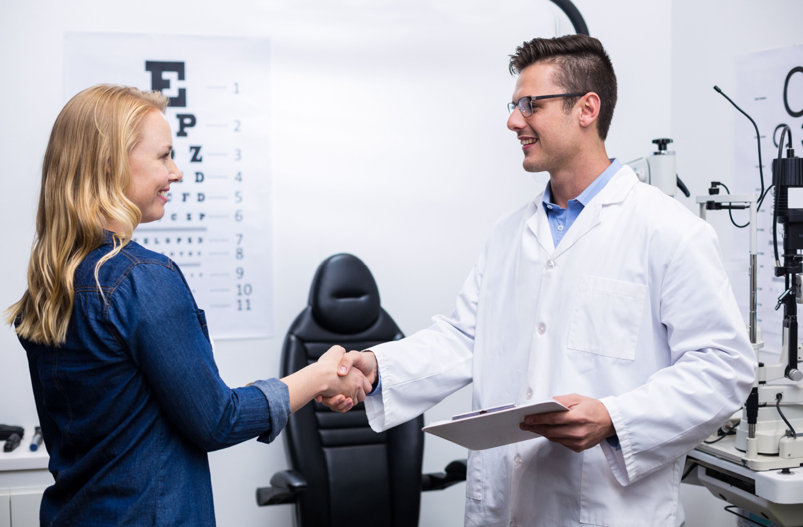 A woman in an optometry clinic shaking hands a male optometrist.