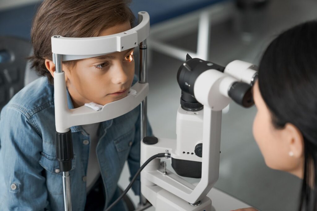 A child has his eyesight examined by an optometrist using a slit lamp.