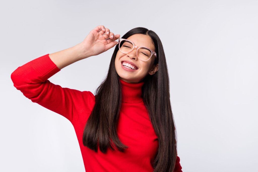 A young woman smiling in her colorful acetate glasses.