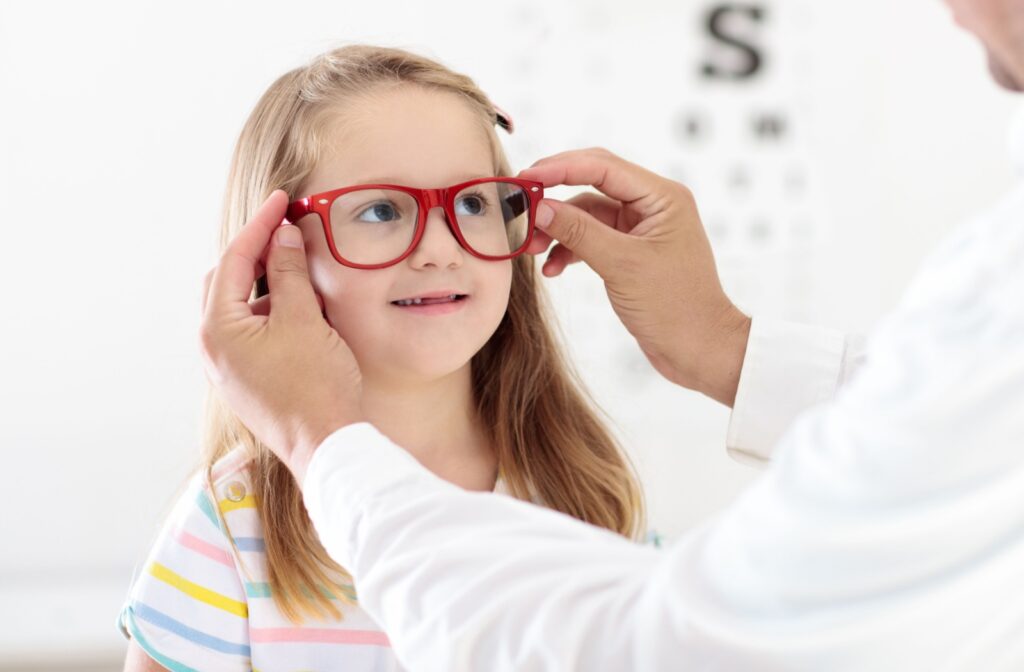A close-up of a young child being fitted for a pair of new glasses after an eye exam.