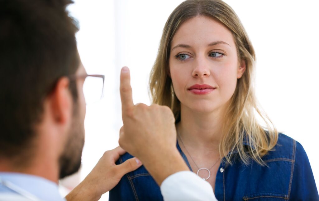 A person follows an optometrist's finger with their eyes to test the strength of their eye muscles in vision therapy.