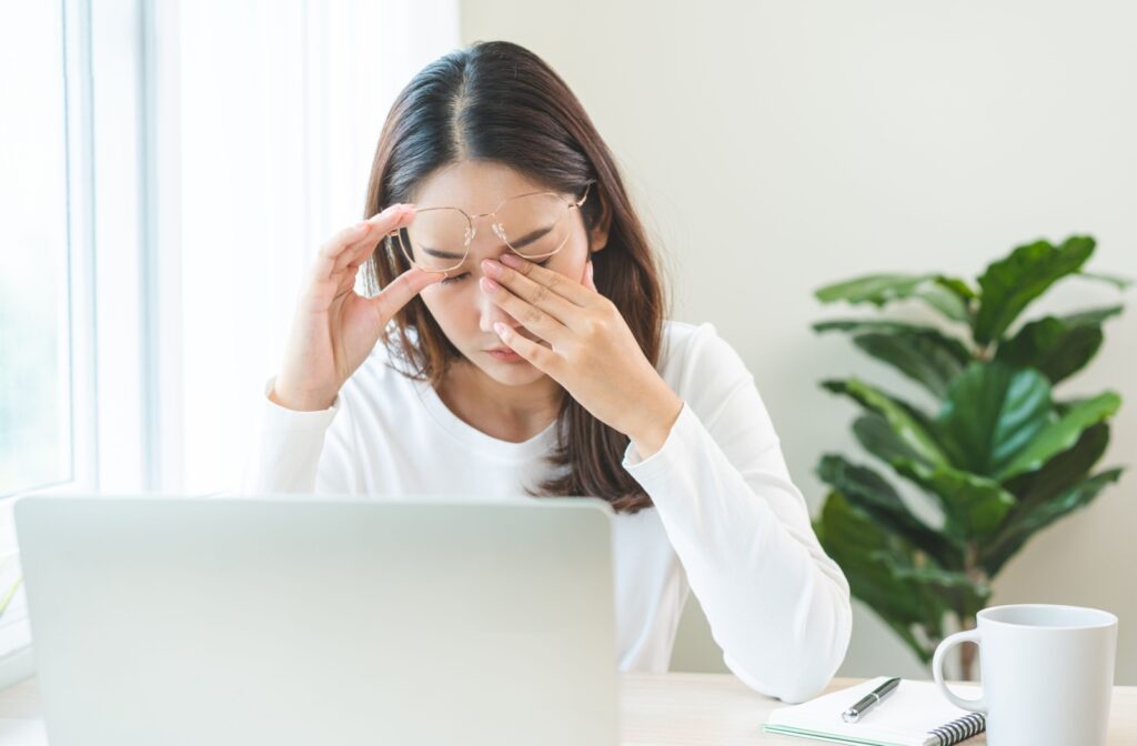 A person working suffers a migraine and rubs one blurry eye.